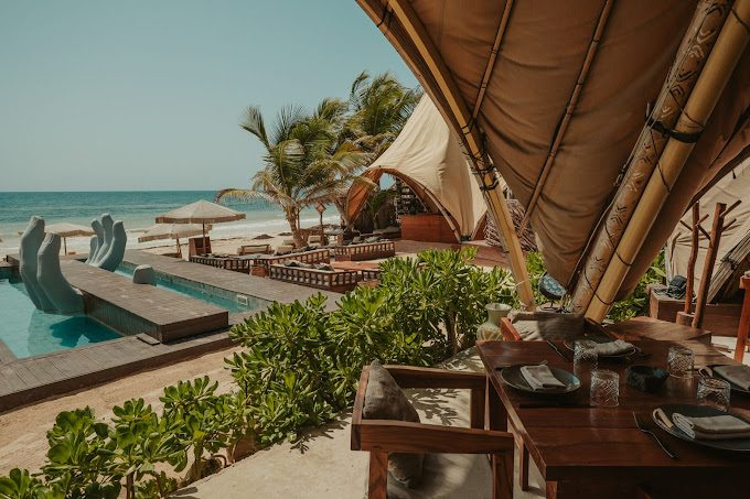 Beachfront daybeds and palm shade at a Tulum hotel zone beach club on the Caribbean sand