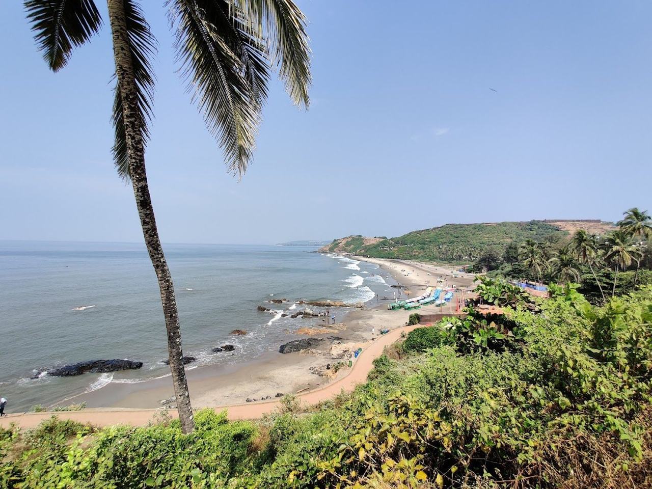 Vagator Beach red cliffs and Chapora headland above the sand in North Goa