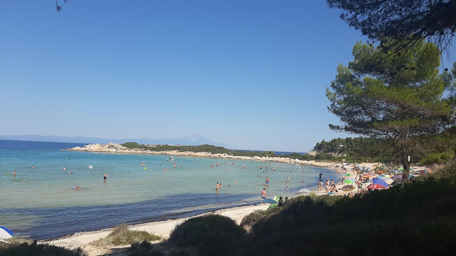 Shallow clear water and golden sand screened by small pine covered islands at Vourvourou on Sithonia in Halkidiki