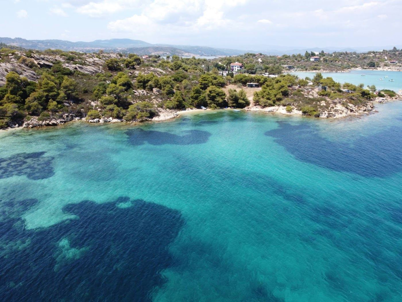 Clear shallow water and small pine covered islands across the bay at Vourvourou on Sithonia in Halkidiki