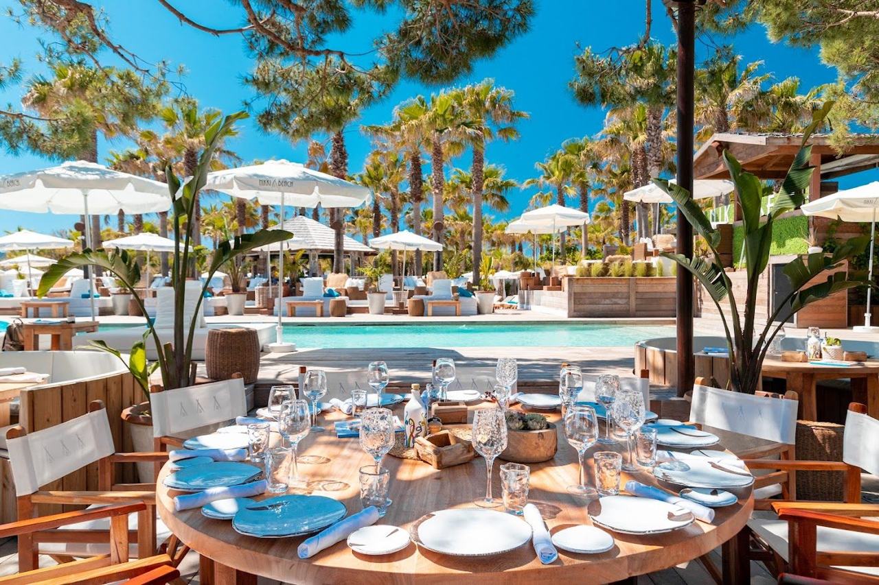 White daybeds and Champagne service on the sand at Nikki Beach Saint-Tropez