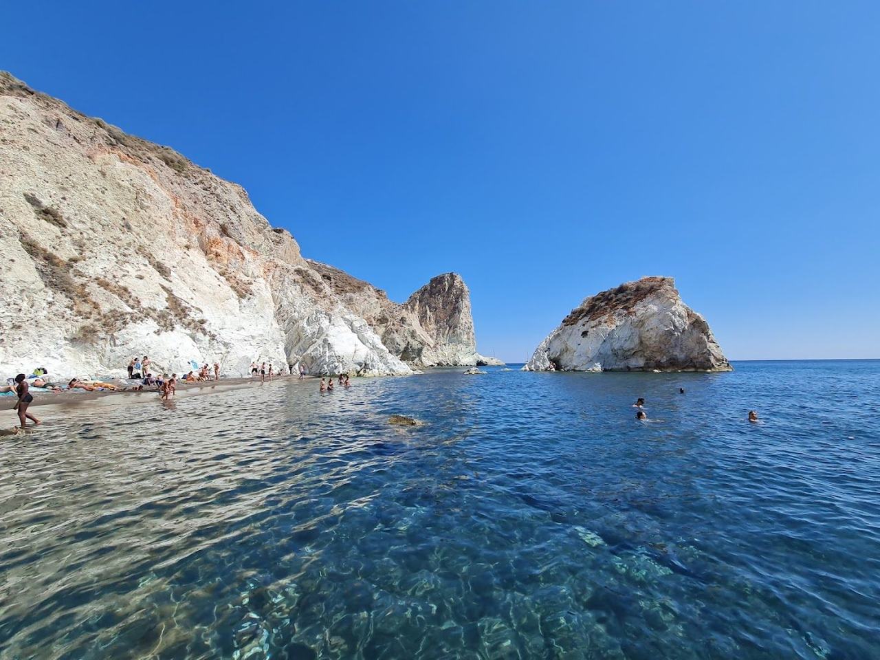 Pale cliffs and a taxi boat at the secluded cove of White Beach near Akrotiri on Santorini