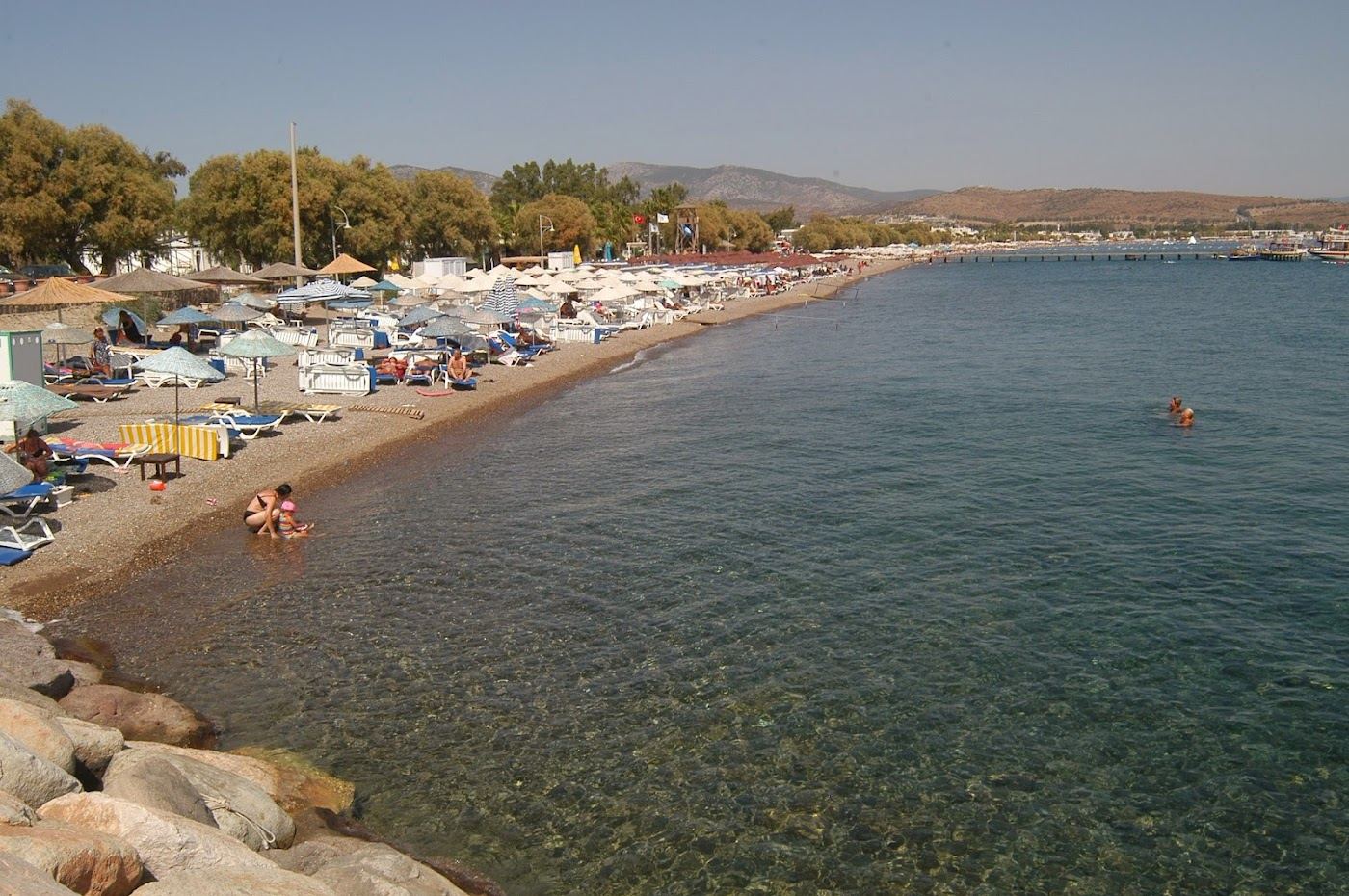 Yahsi long sandy beach at Ortakent on the Bodrum peninsula with shallow water and beach clubs along the shore in Turkey